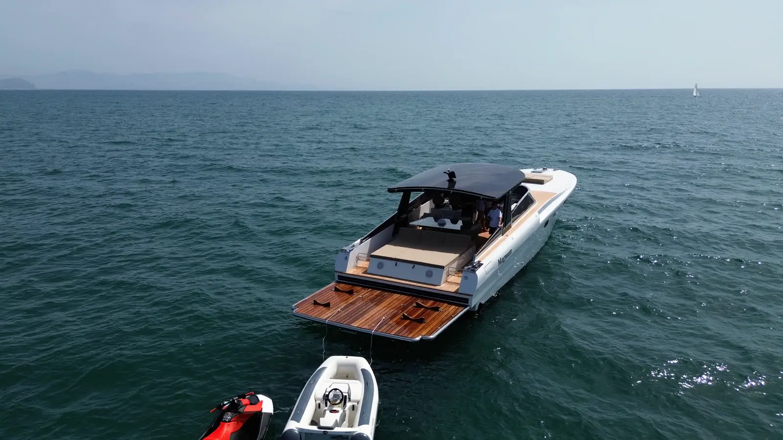 Magnum all'ancora in rada con tender e moto d'acqua a poppa